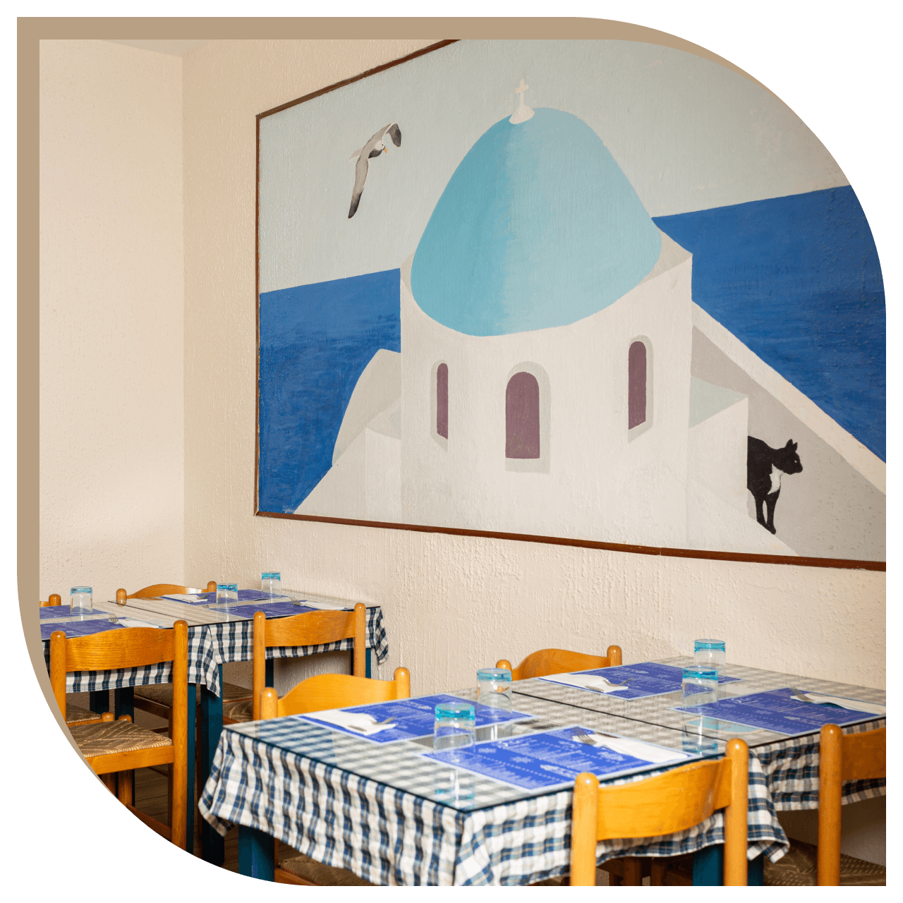 Sala del Ristorante El Greco di Bologna con affresco ispirato a Santorini e tavoli apparecchiati.