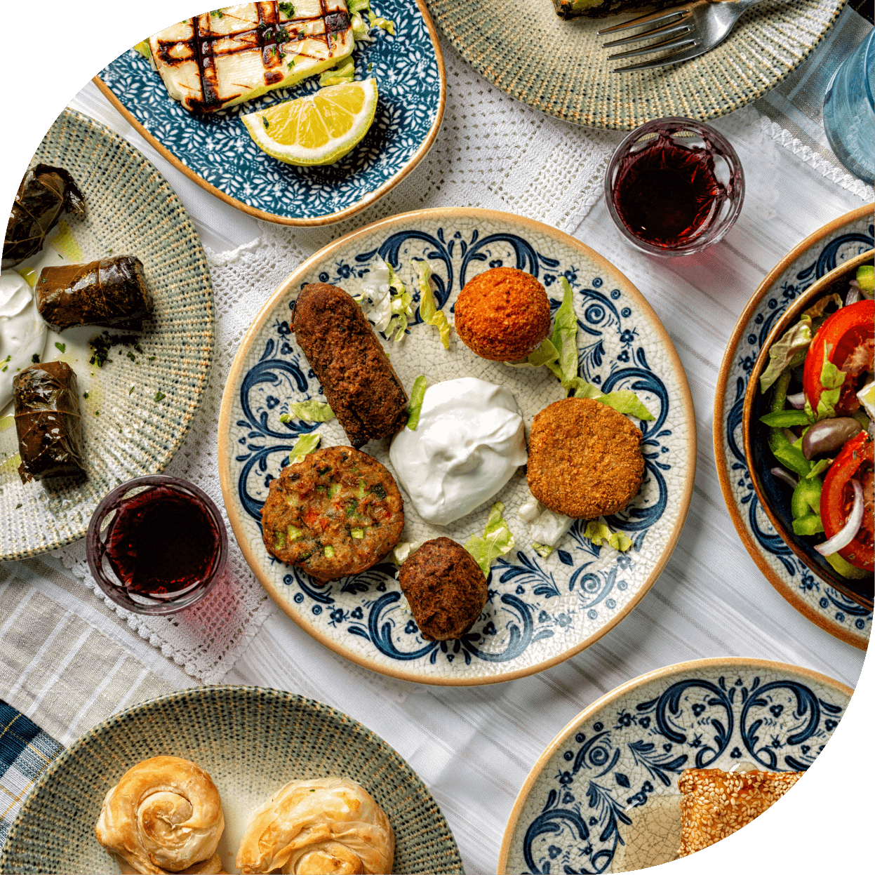 Piatti tipici greci del Ristorante El Greco di Bologna con antipasti misti e vino rosso serviti su ceramiche decorate.