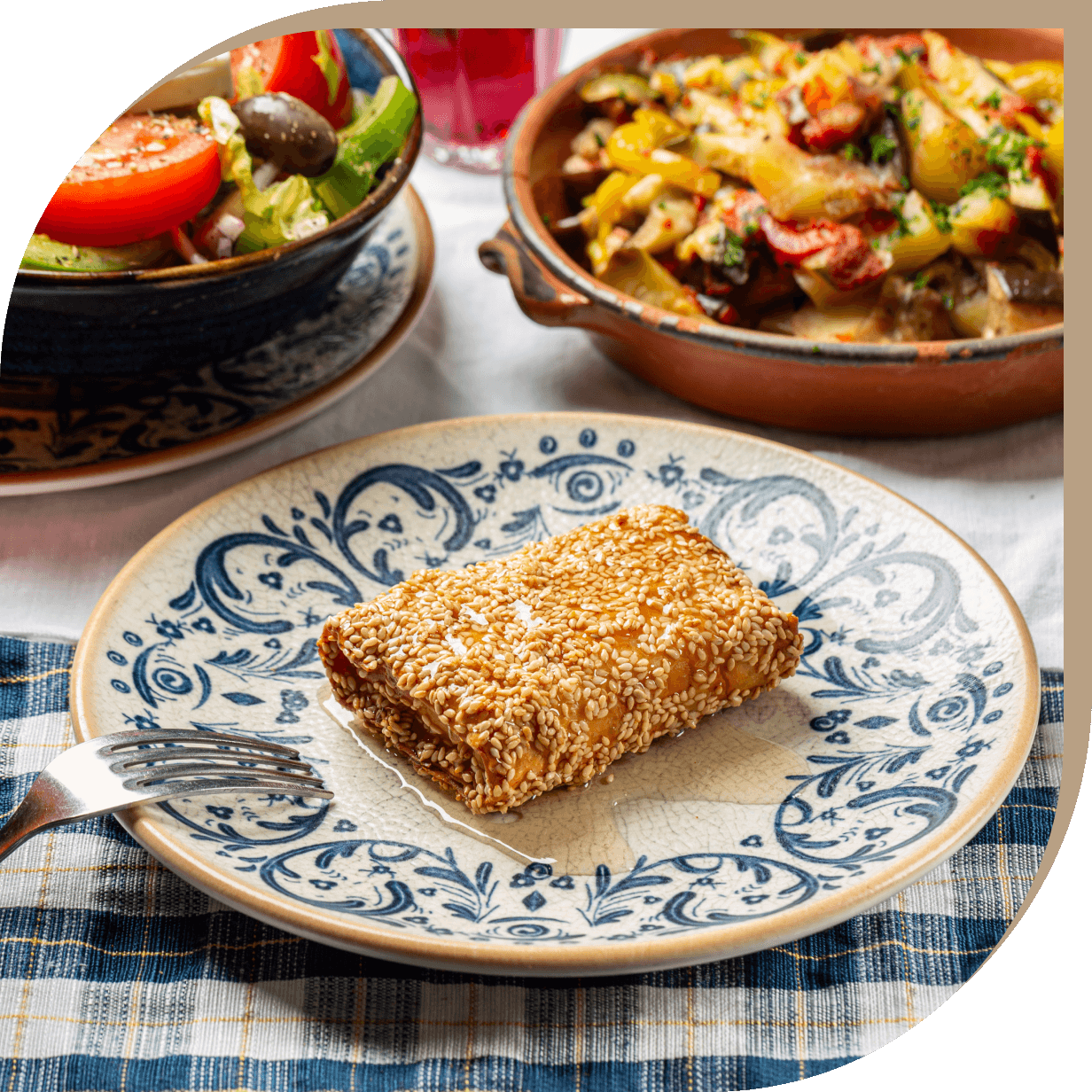 Saganaki del Ristorante El Greco di Bologna, formaggio greco fritto con miele e semi di sesamo servito su ceramiche decorate.