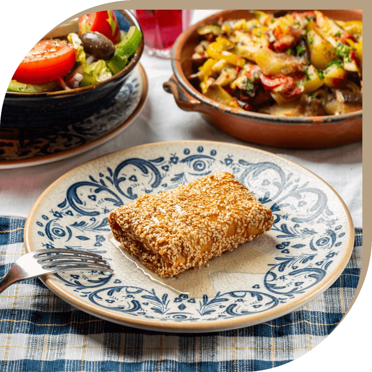 Saganaki del Ristorante El Greco di Bologna, formaggio greco fritto con miele e semi di sesamo servito su ceramiche decorate.