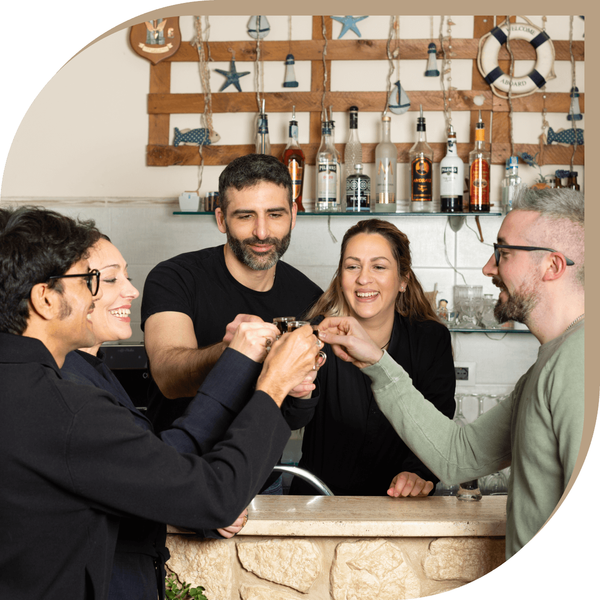 Staff e clienti del ristorante greco tradizionale El Greco di Bolognina brindano insieme al bancone.