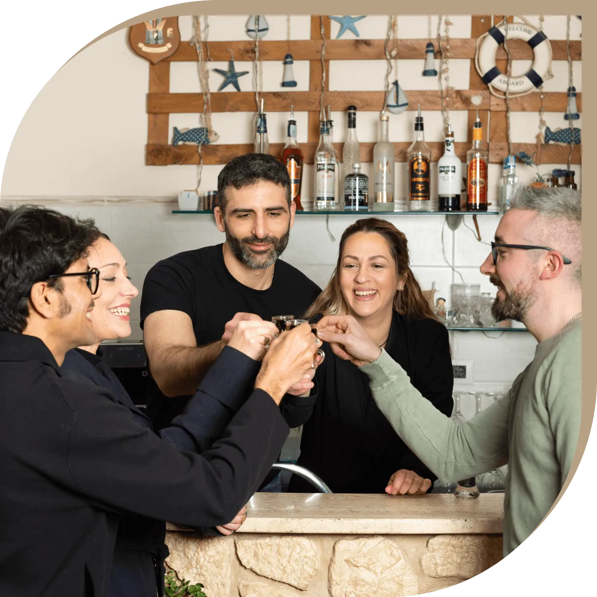 Staff e clienti del ristorante greco tradizionale El Greco di Bolognina brindano insieme al bancone.