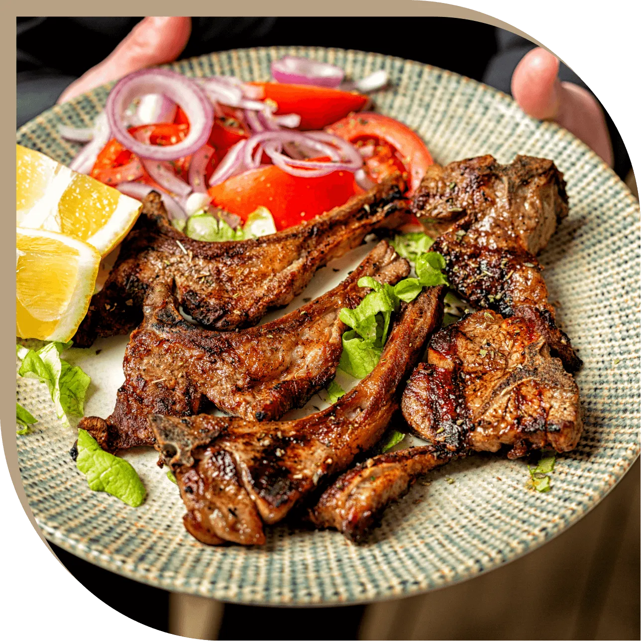 Costolette di agnello alla griglia con insalata fresca di pomodori e cipolla del Ristorante El Greco di Bologna.