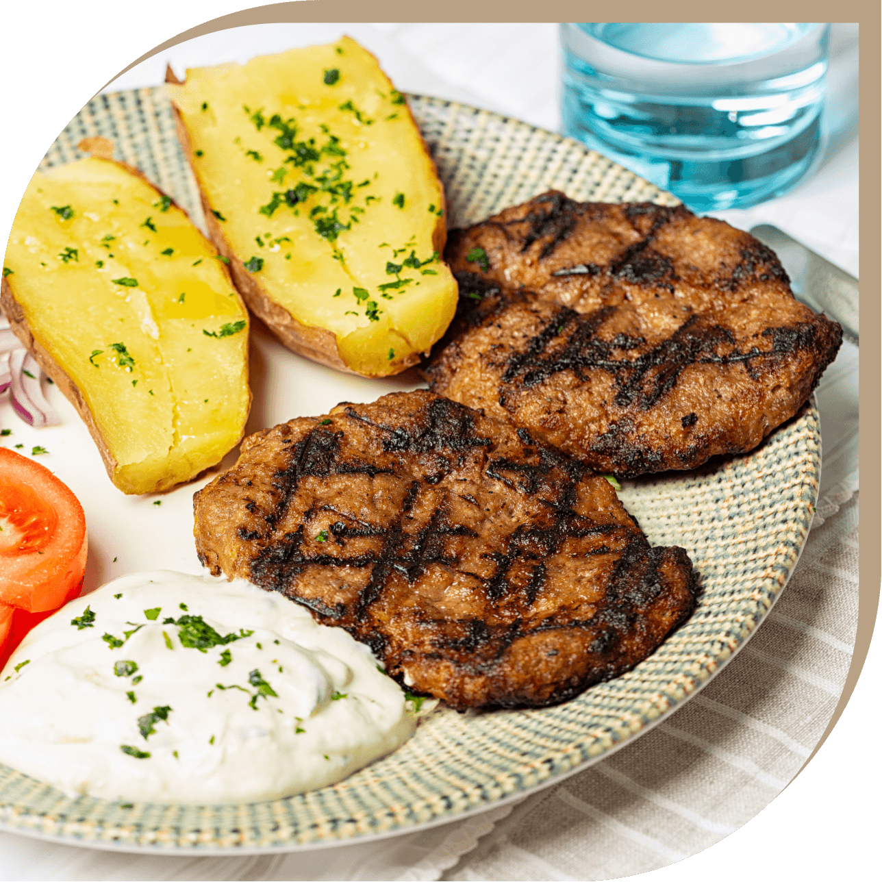 Bifteki del Ristorante El Greco di Bologna, hamburger greco alla griglia con patate al forno, pomodoro fresco e salsa tzatziki.