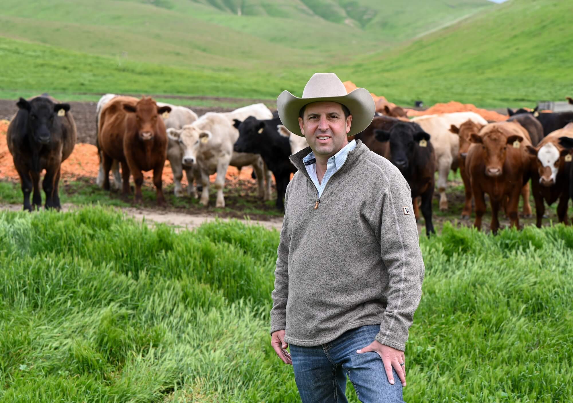 Justin Pettit standing in front of his cattle on his ranch