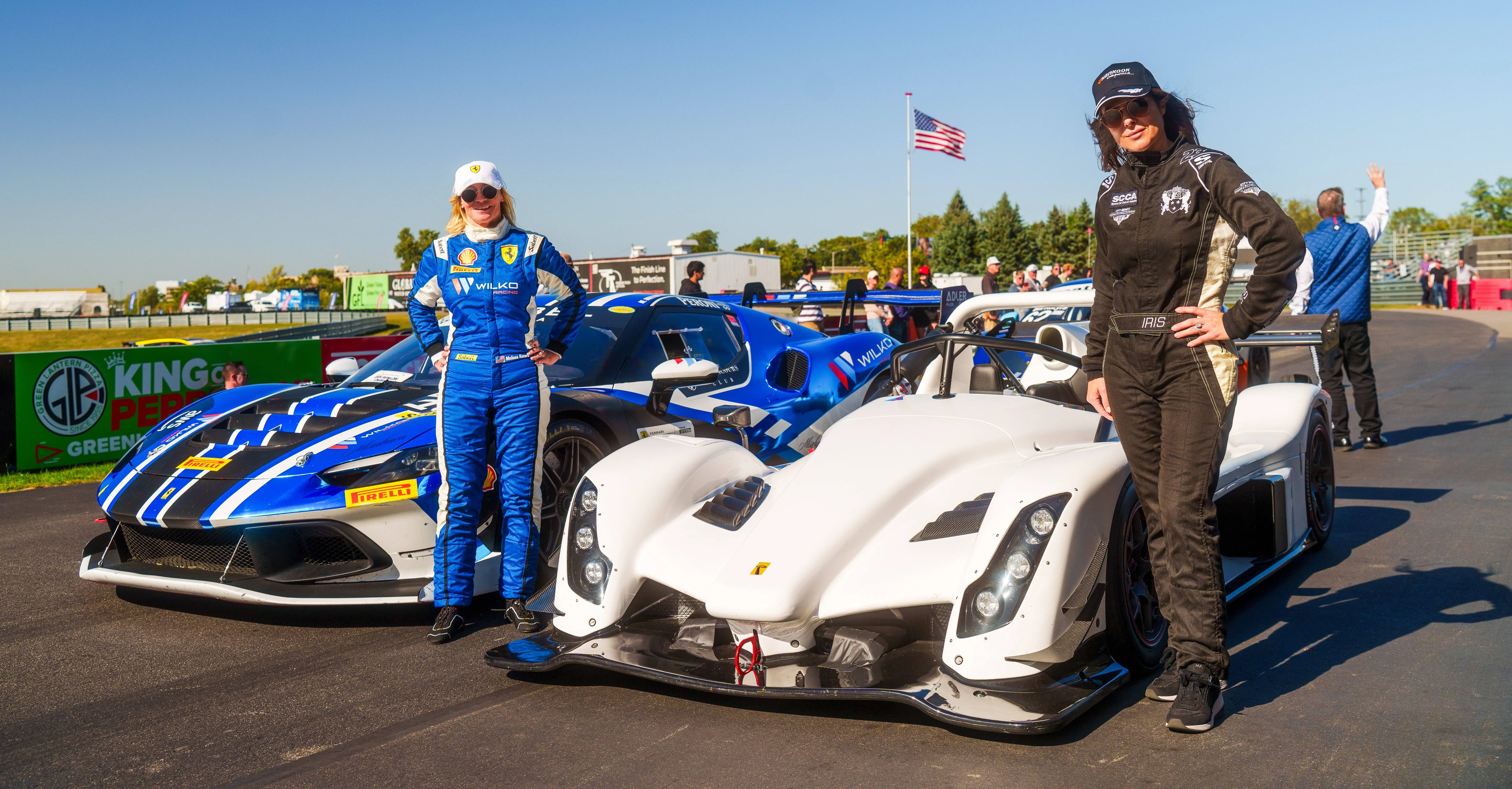 2 women racers posing by their race cars. One car is a Ferrari and the other car is a Radical.