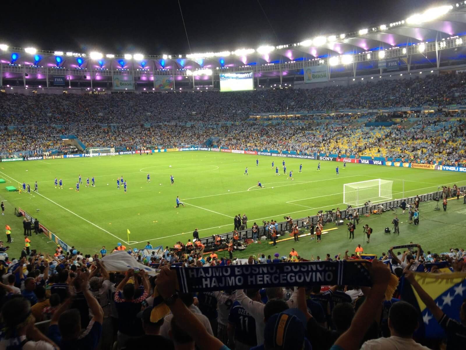 Bosnia players at football field with supporters at the stands