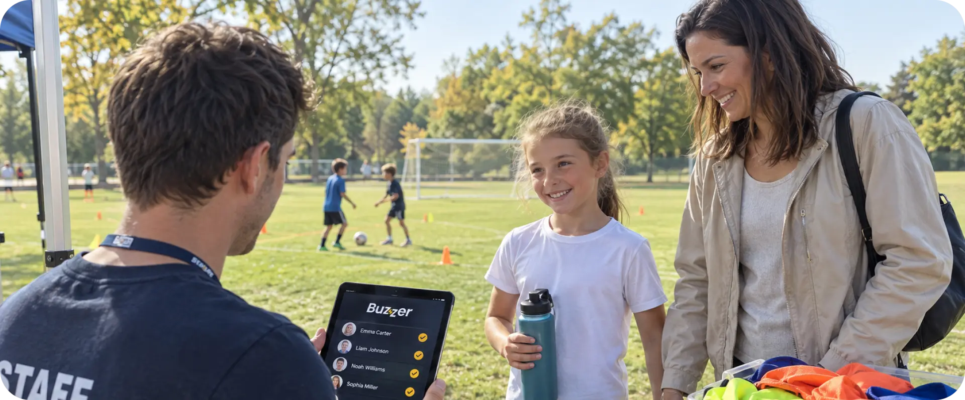 Staff member checking in a young player and parent on a tablet registration list at a soccer camp