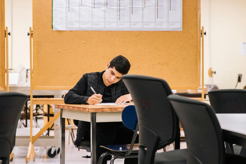 a student taking an exam in a classroom separated to avoid ai plagiarism