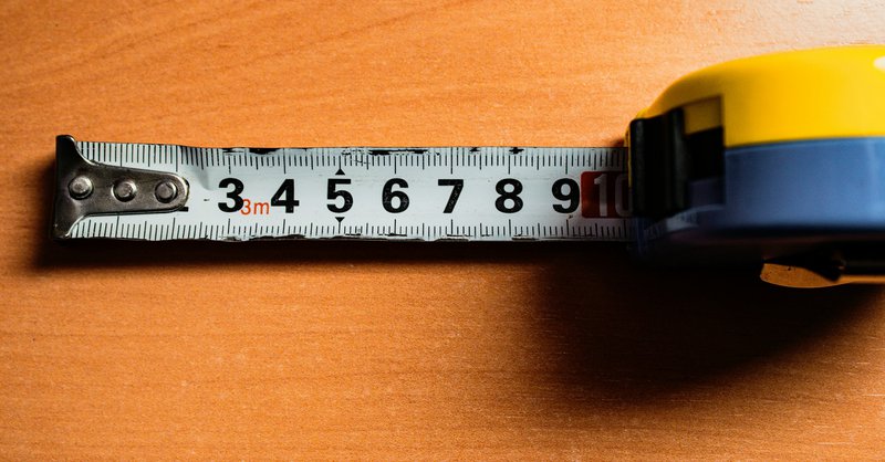 A tape measure is on a wooden table symbolizing program measurement from a grant evaluation plan
