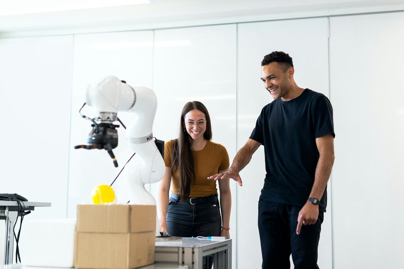 a man and a woman looking at a robotic arm, symbolizing SBIR grant application technology readiness levels