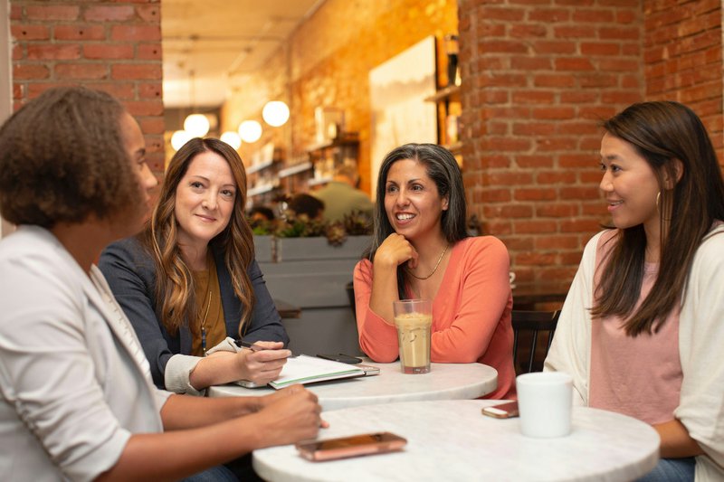 four women having a meeting around two tables perhaps having a project staff meeting as part of a grant writing team workflow