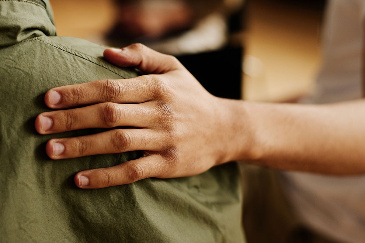 someone touching someone elses back in support