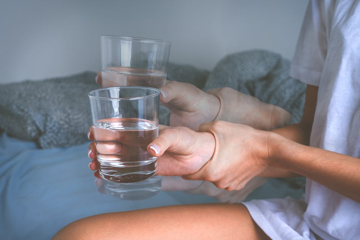 Woman's hands shaking while holding a glass