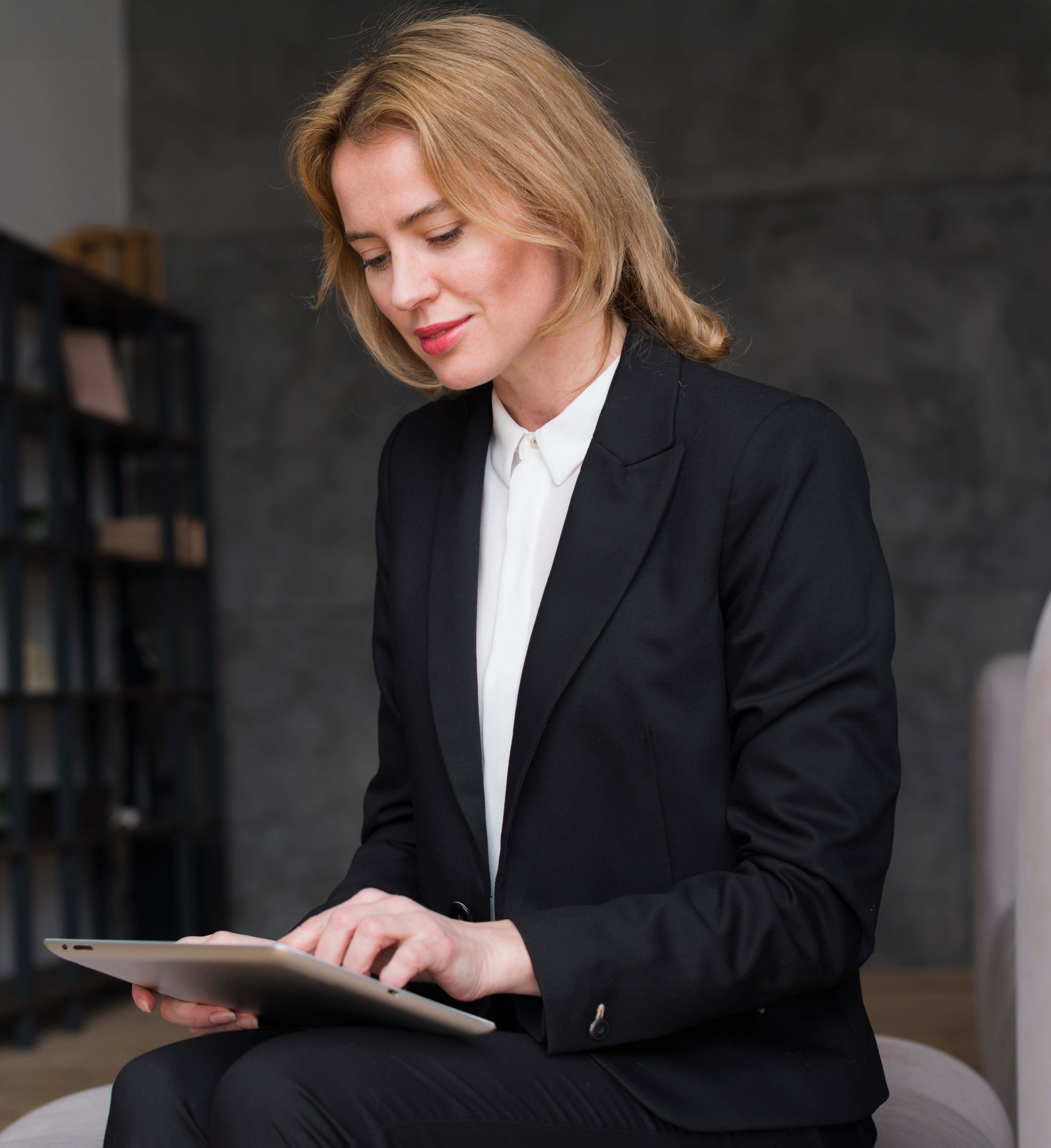 Focused businesswoman in black suit using a tablet in office environment