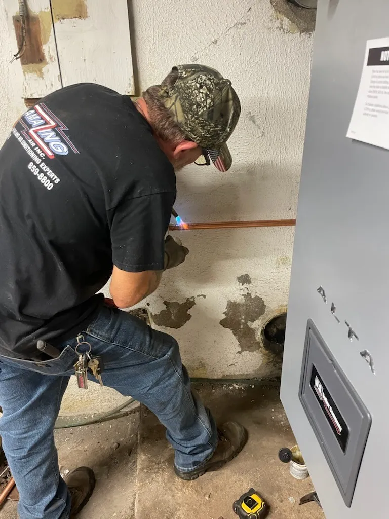 Technician working on water heater and plumbing in utility room