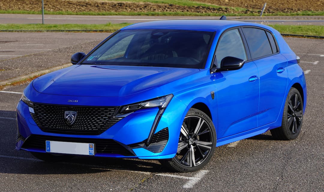 Vue avant et latérale d'une Peugeot 308 bleue moderne, garée sur un parking, illustrant son design élégant.
