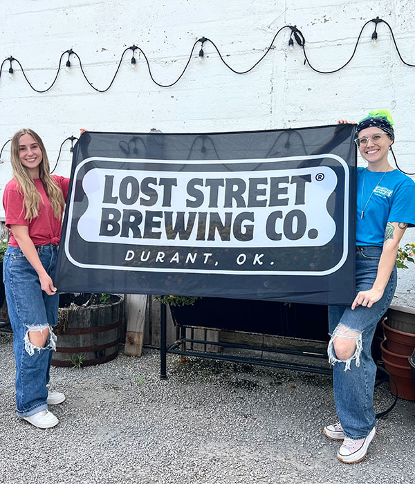 A Photo of two Women holding up a Lost Street Brewing Co sign