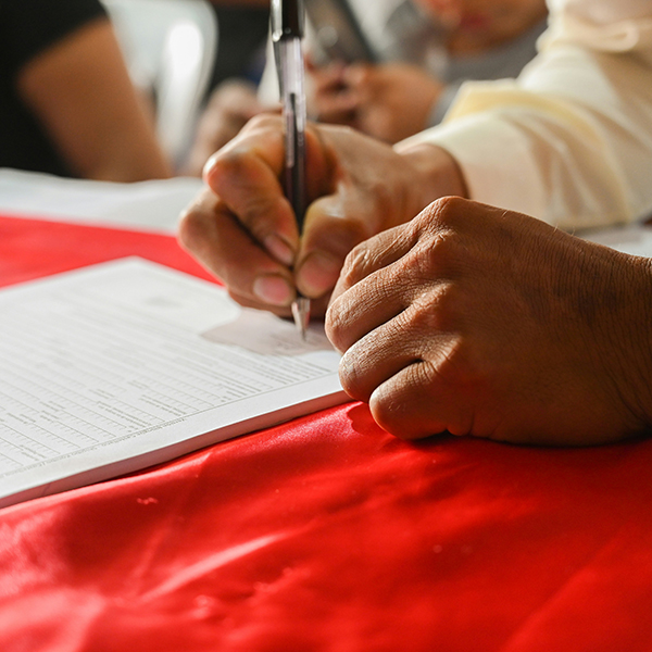 Photo of a man signing a piece of paper