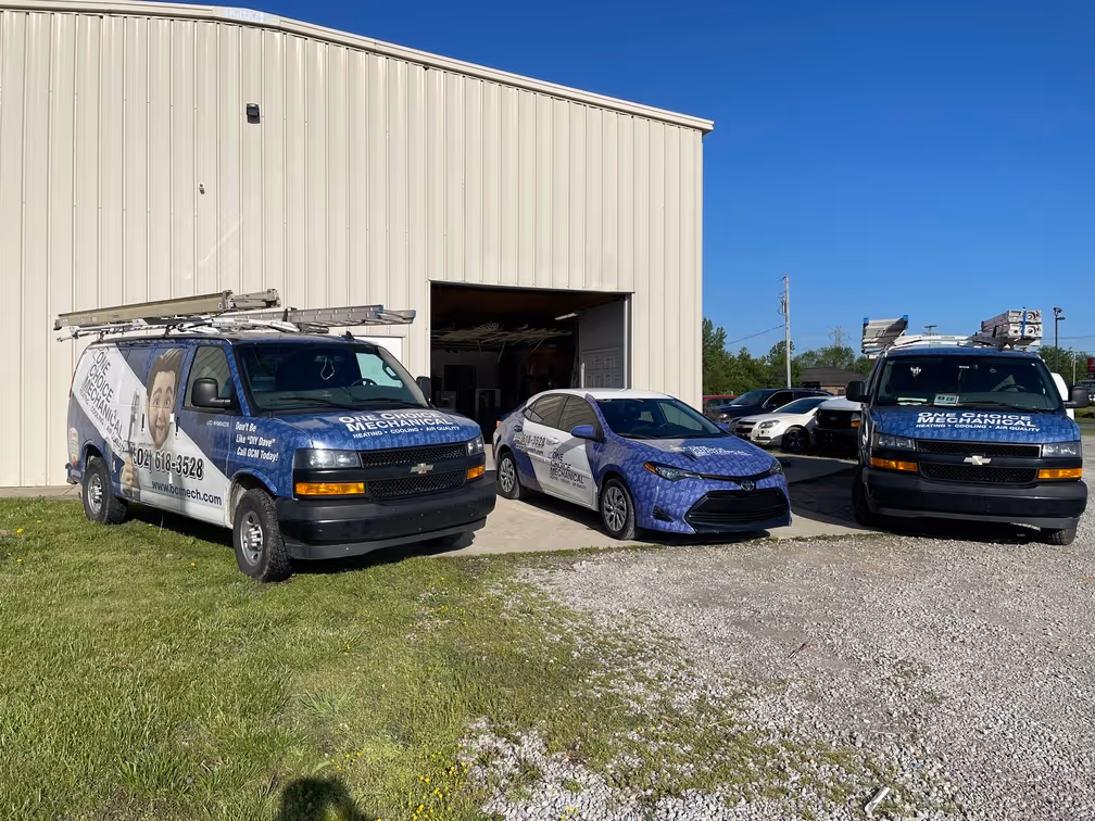 Three blue and white service vans parked outside a warehouse building