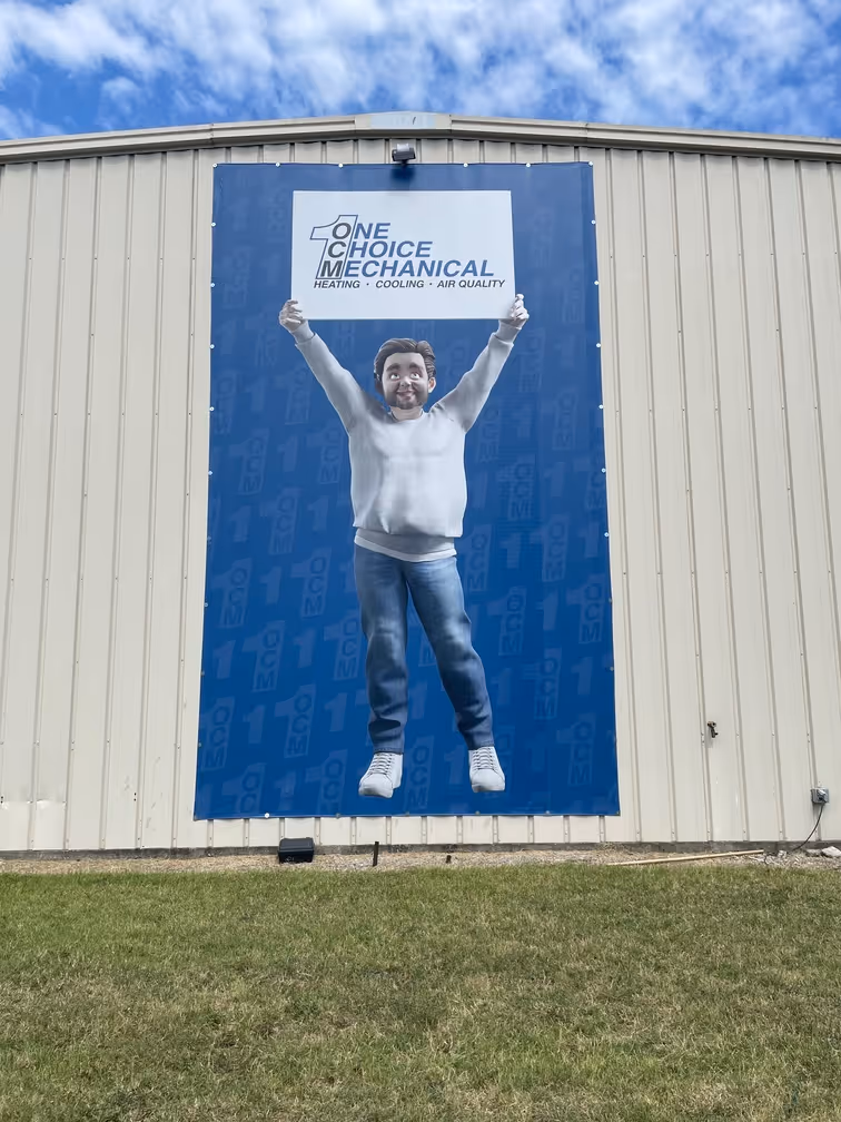 Excited figure holding One Choice Mechanical logo on blue building wall