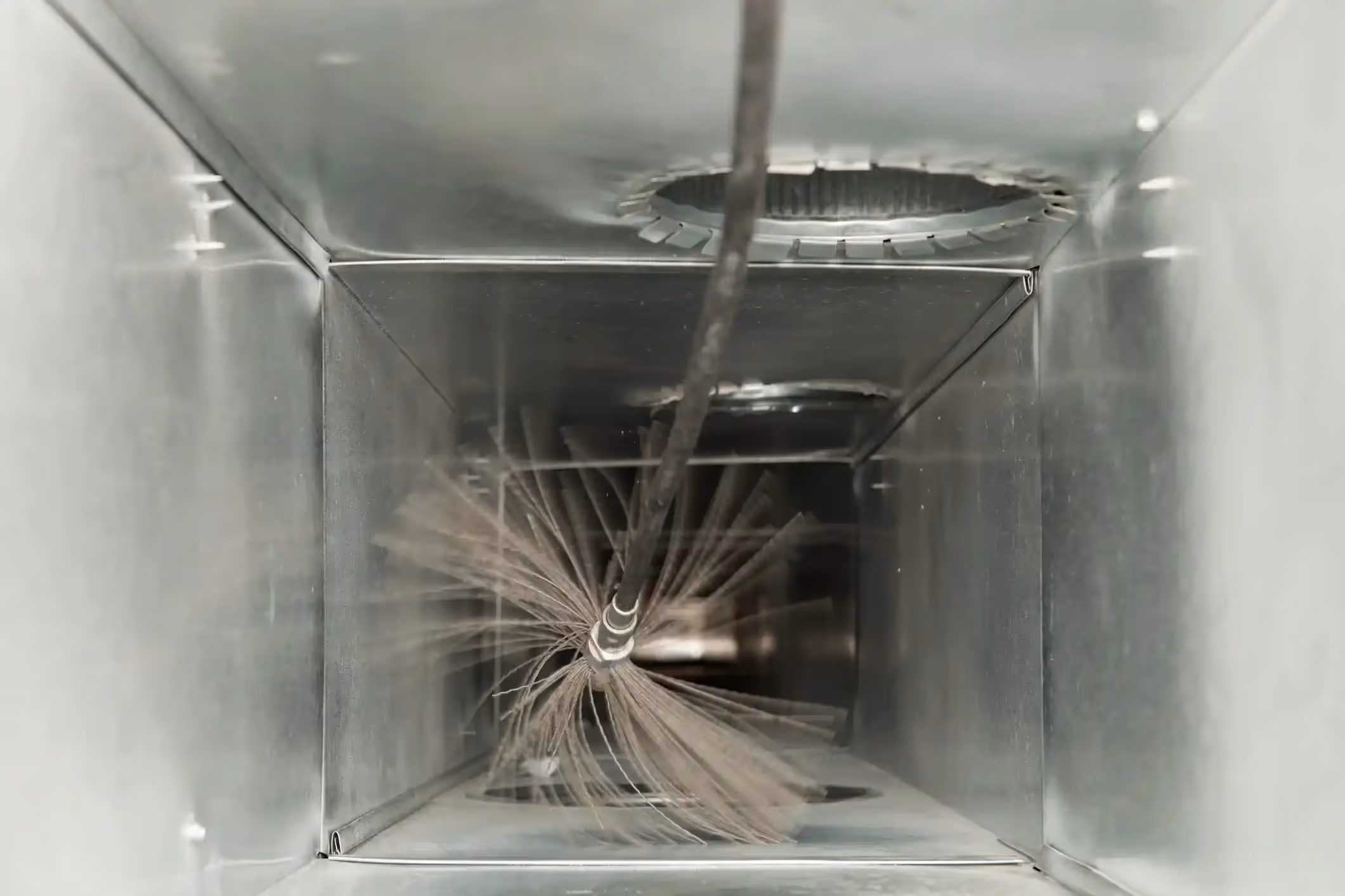 Cleaning brush inside metal air duct during HVAC maintenance process
