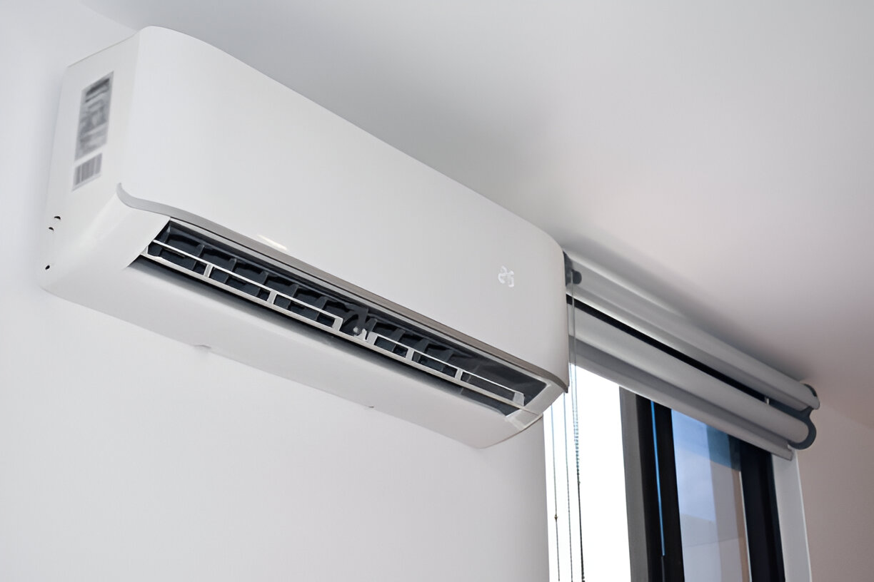 Modern white air conditioning unit mounted on wall near window