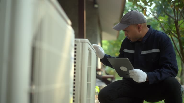 Technician in dark uniform checking outdoor equipment with tablet
