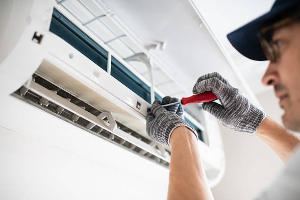 Technician installing or repairing air conditioning unit with tools