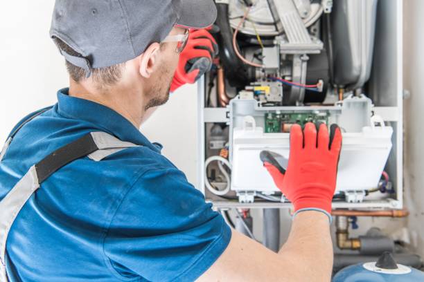 Technician in blue jacket repairs industrial electrical equipment with red gloves