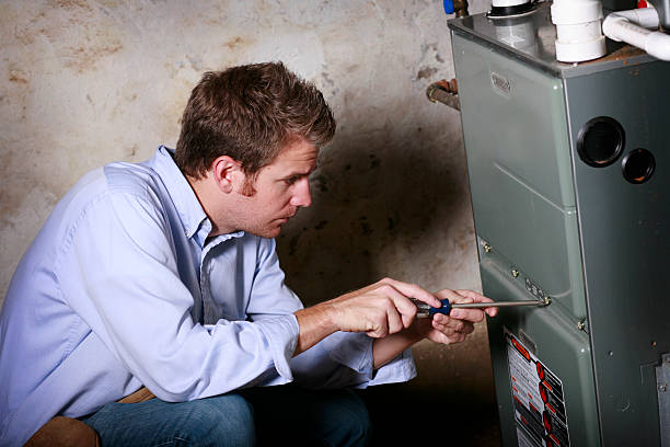 Technician inspecting and repairing a residential heating system or furnace