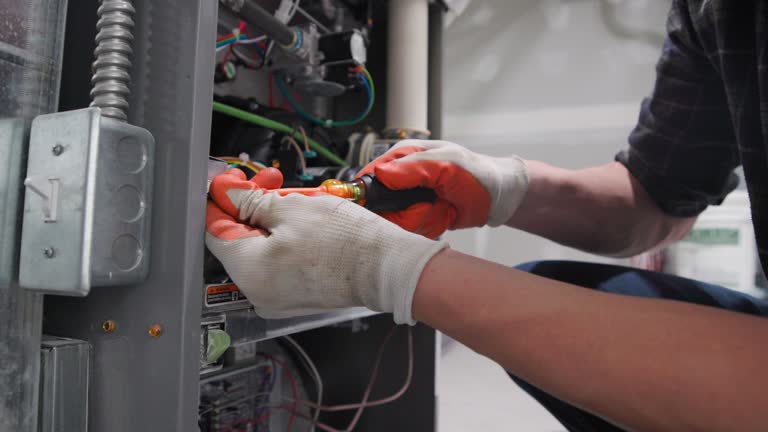 Electrician in gloves working on electrical panel with colorful wires
