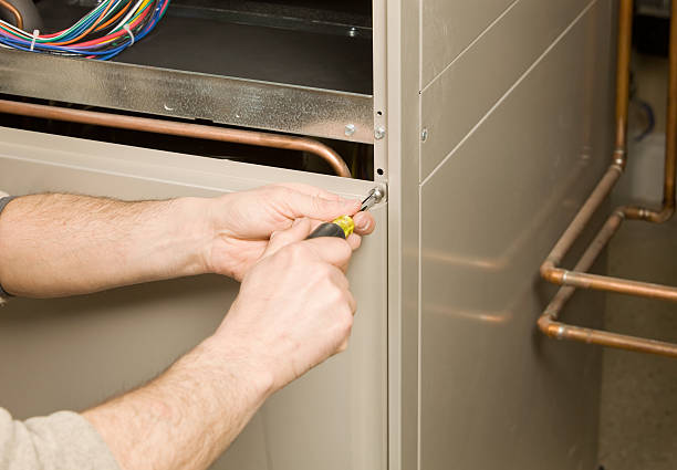 Hands using screwdriver to adjust electrical wiring in metal panel