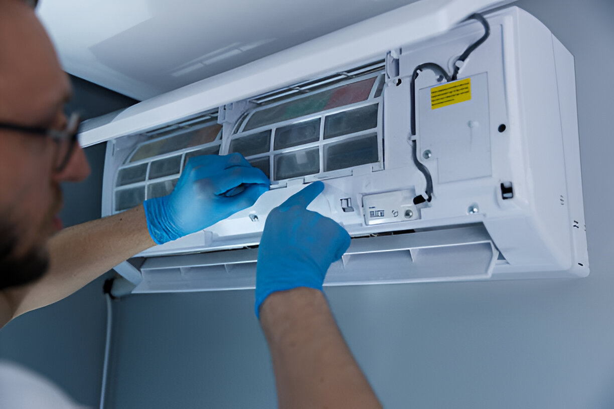 Technician in blue gloves repairing and cleaning an air conditioning unit