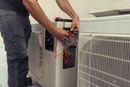 Person holding tool near air conditioning unit or HVAC system