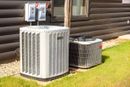 White air conditioning unit installed outside a wooden-sided building