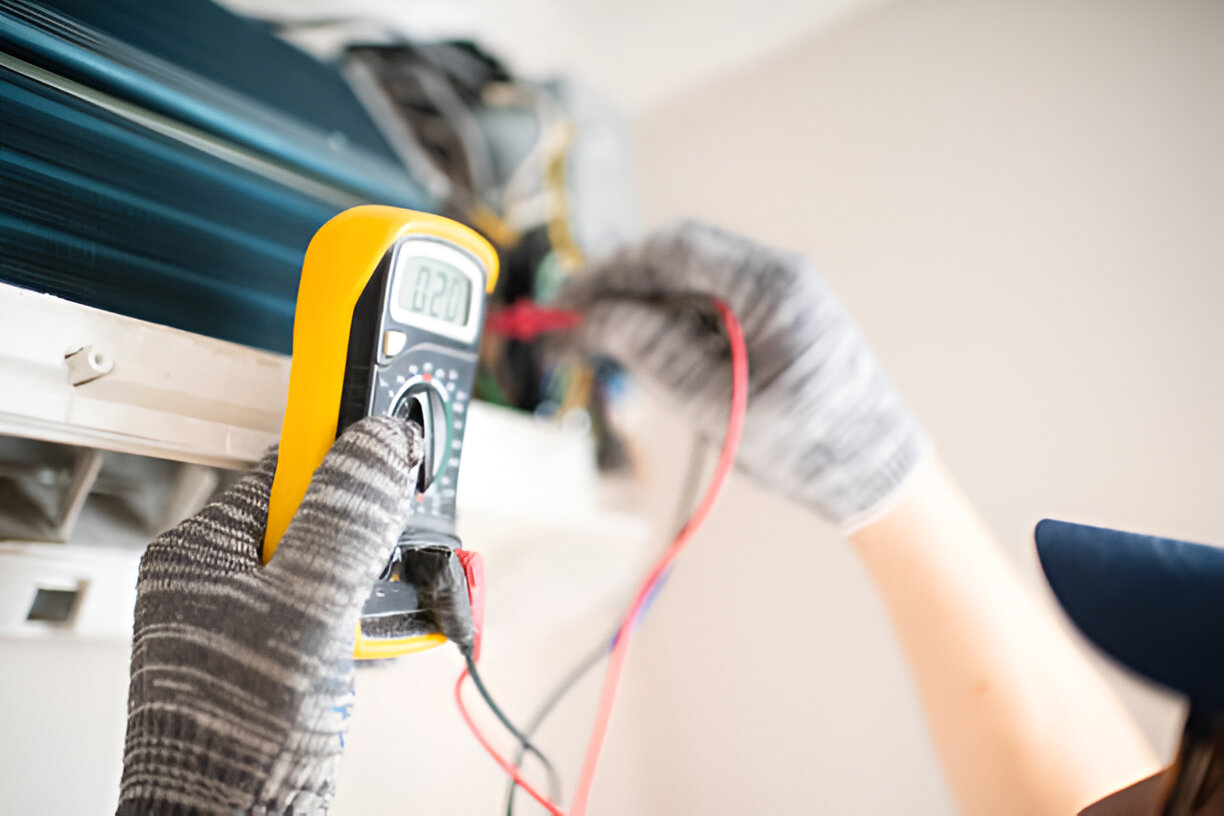 Electrician using multimeter to measure voltage with protective gloves