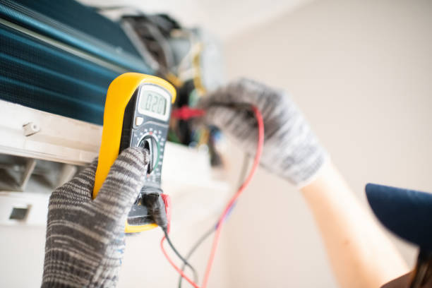 Technician using multimeter to check electrical connections with gloved hands