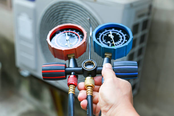 Technician checking pressure gauges on HVAC refrigeration manifold