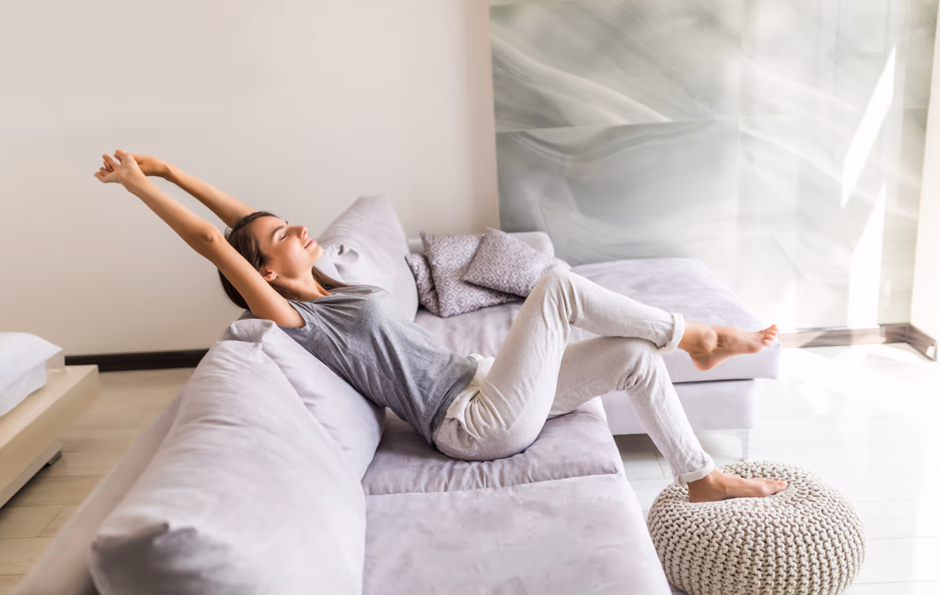 Woman stretching and relaxing on a comfortable couch at home