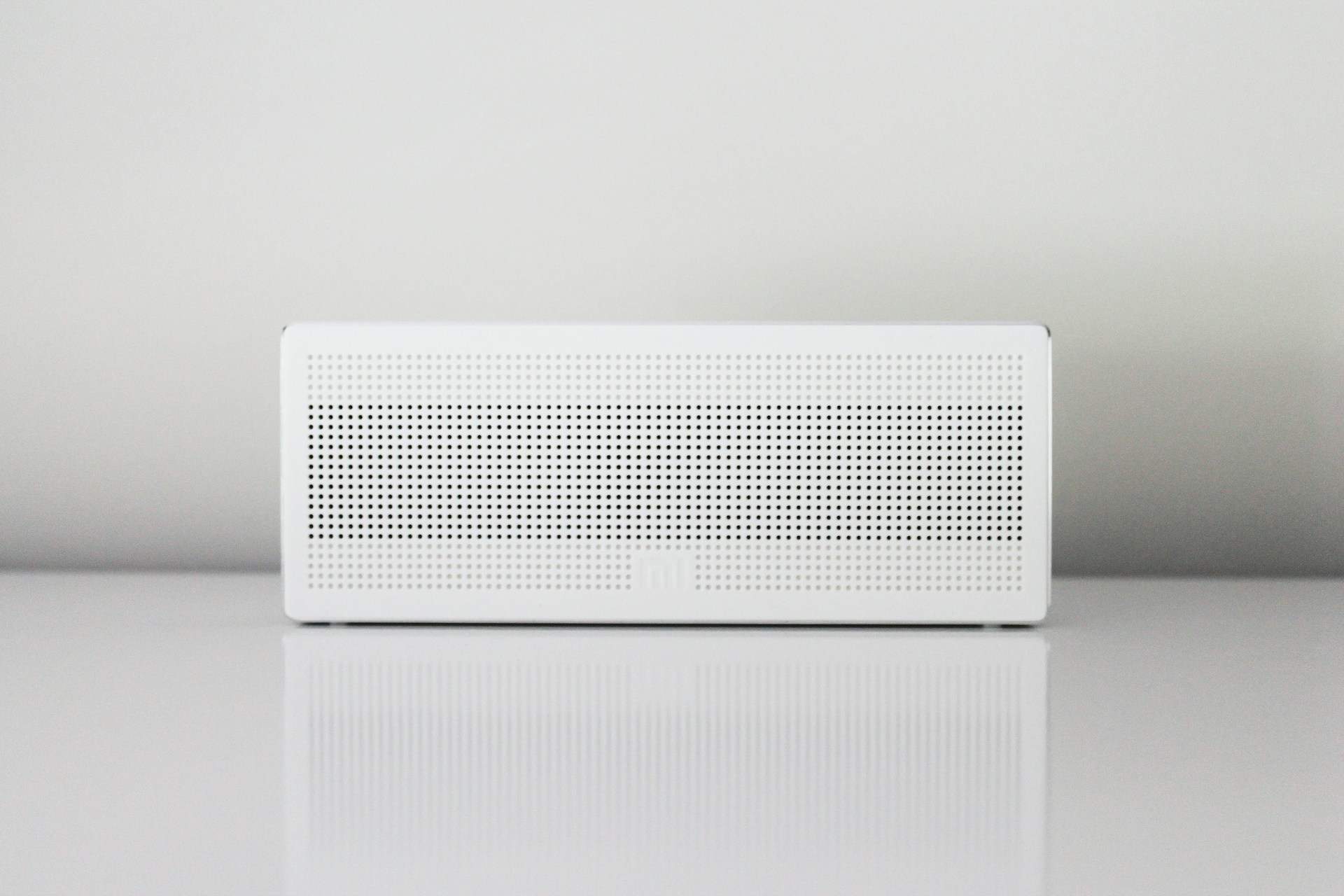 White rectangular speaker with perforated design on minimalist background