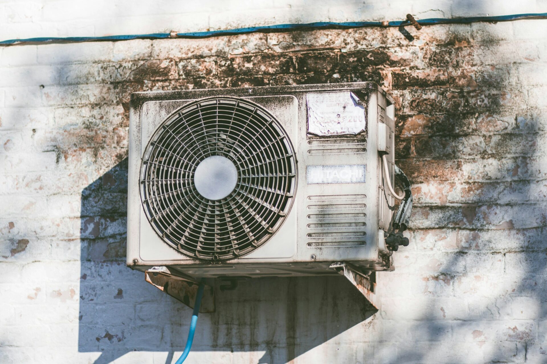 Old air conditioning unit mounted on weathered brick wall