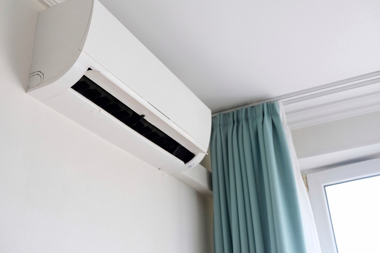 White wall-mounted air conditioner with teal curtains in modern room