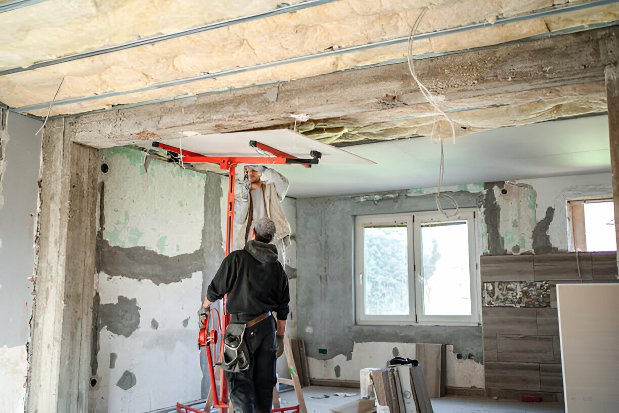 Worker installing insulation on ceiling during home renovation project