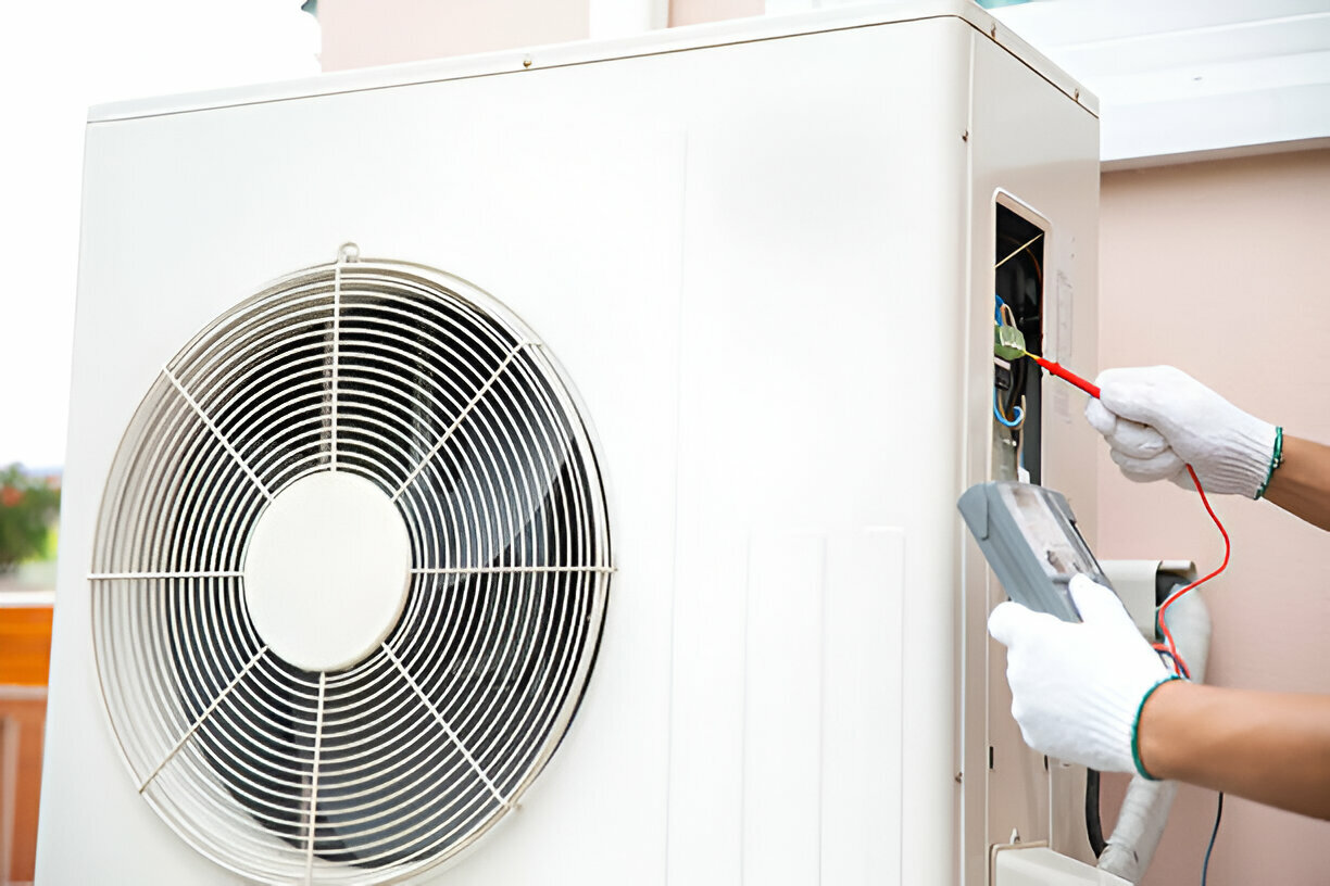 Technician repairing air conditioning unit with electrical testing equipment