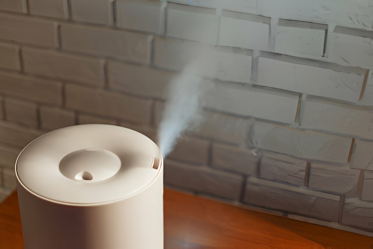 White air humidifier emitting steam against brick wall background