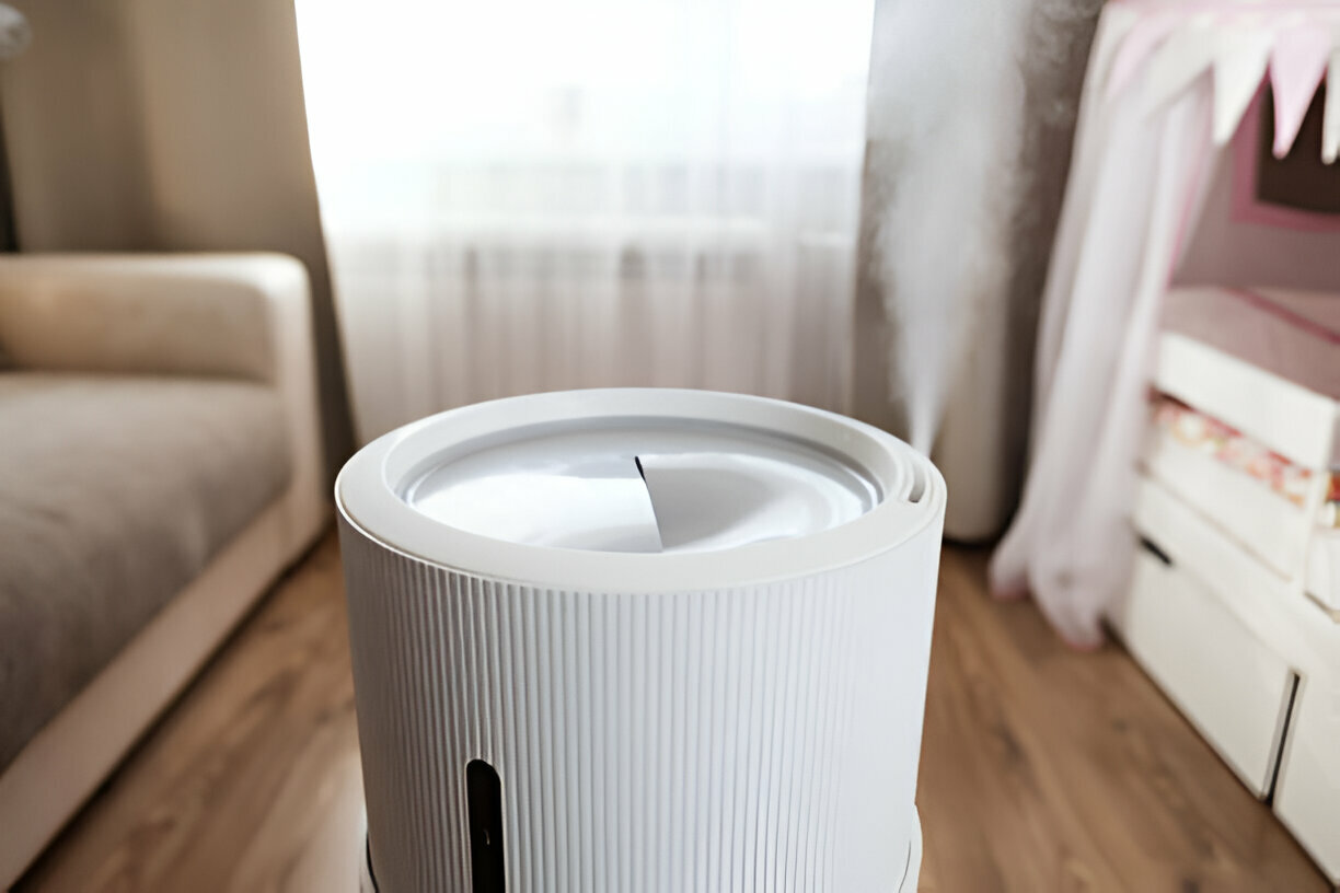 White air purifier on wooden floor near couch and window