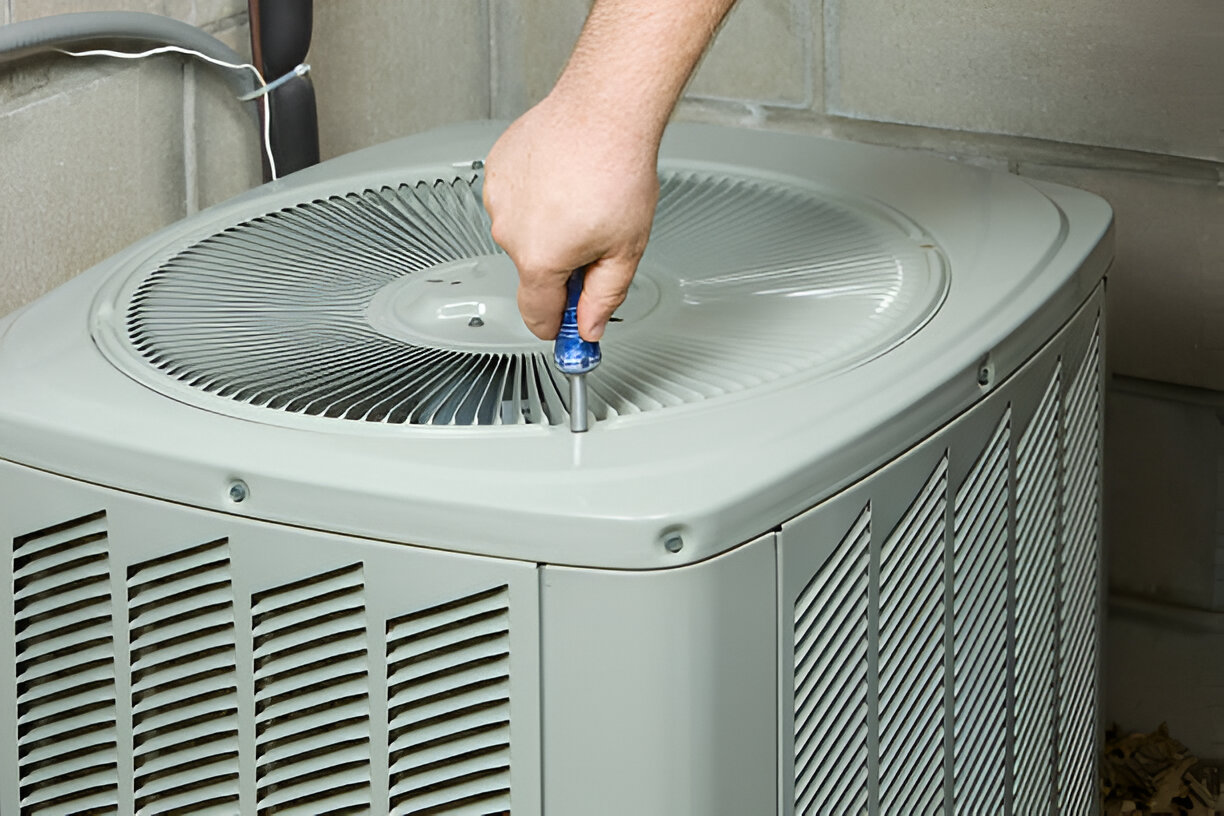 Technician repairing air conditioning unit with screwdriver