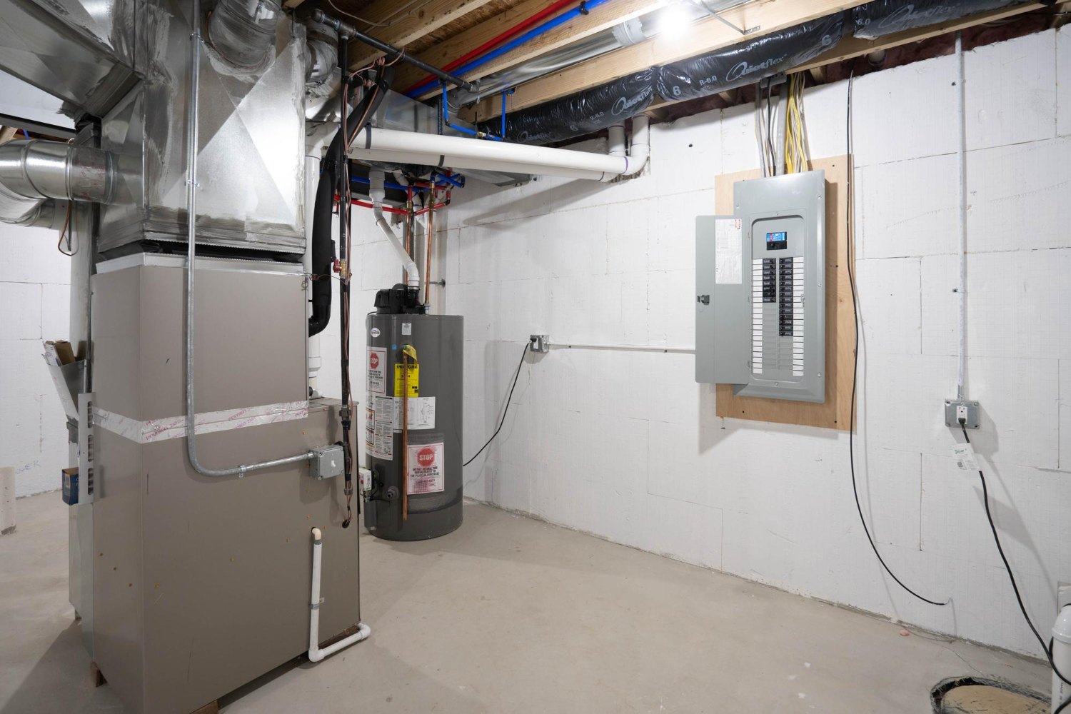 Basement utility area with furnace, water heater, and electrical panel.