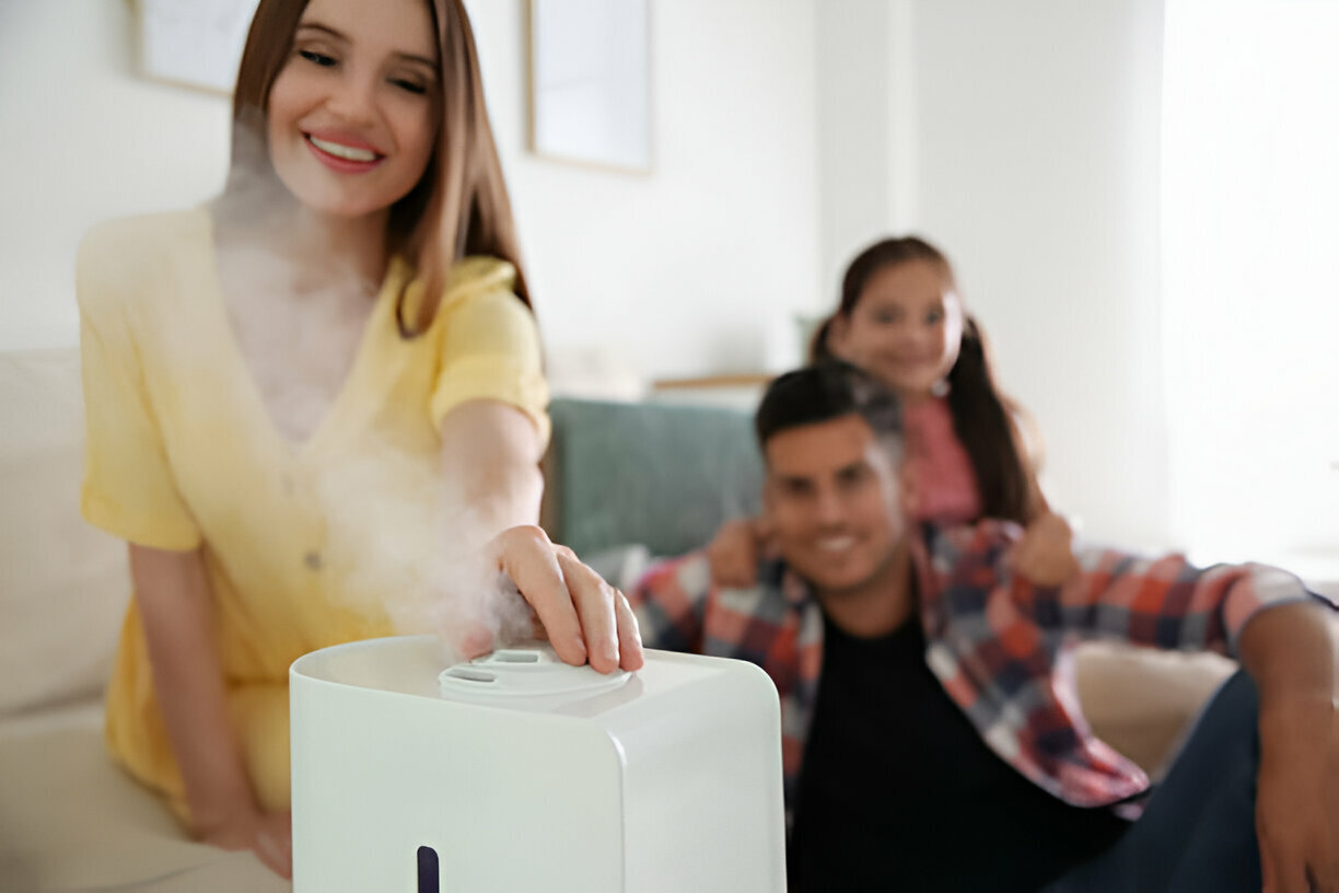 Woman using air purifier with family in background at home